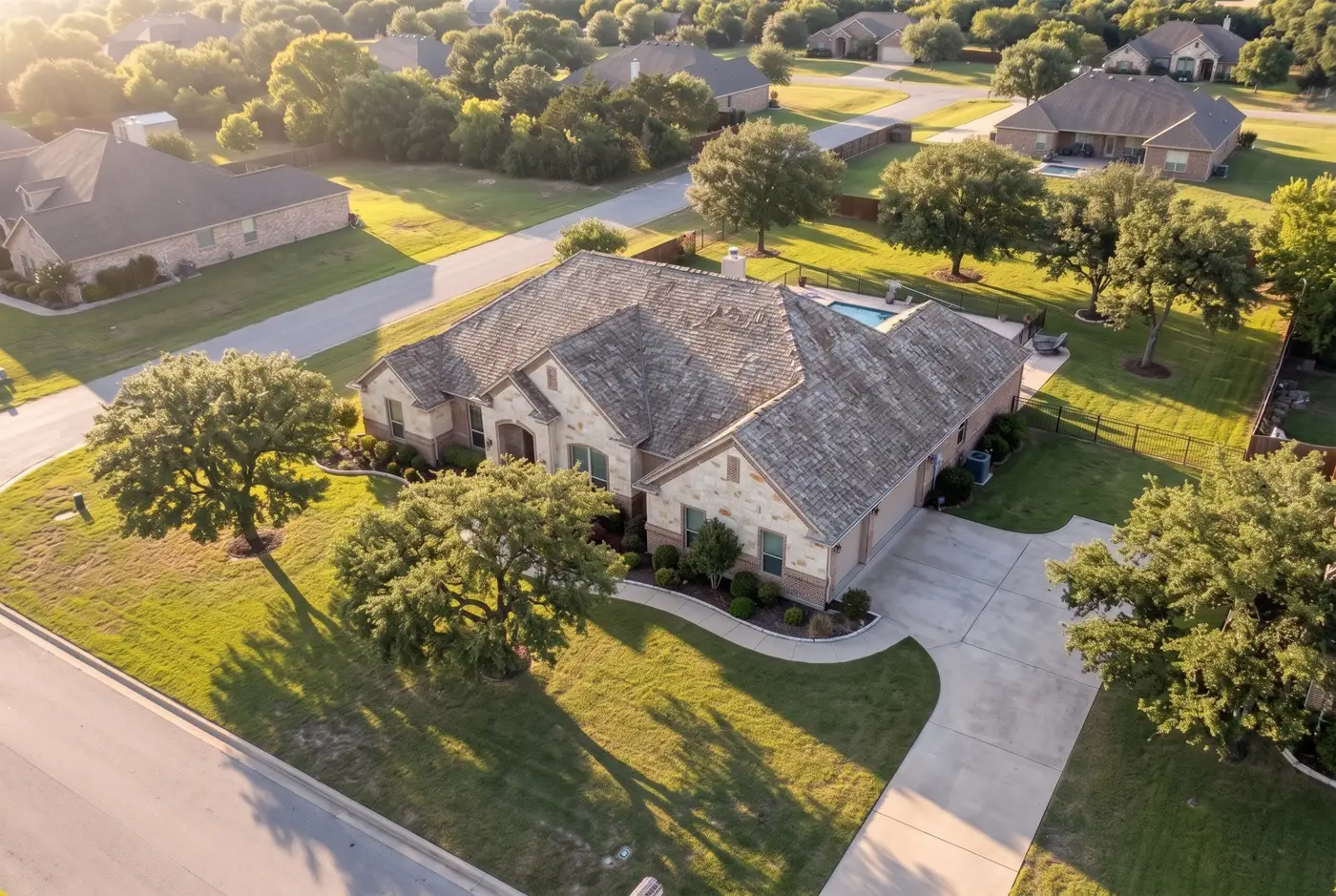 Drone view of a ranch home with faded, curling shingles